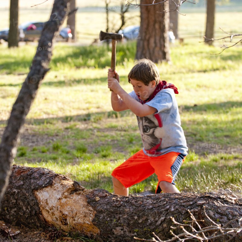 Caucasian boy chopping log with axe
