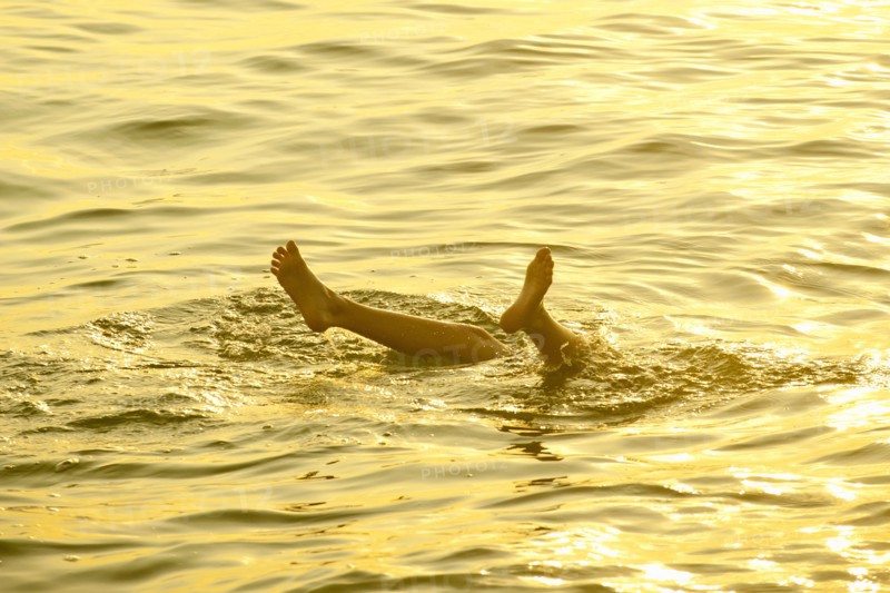Feet of Caucasian boy sticking out of water