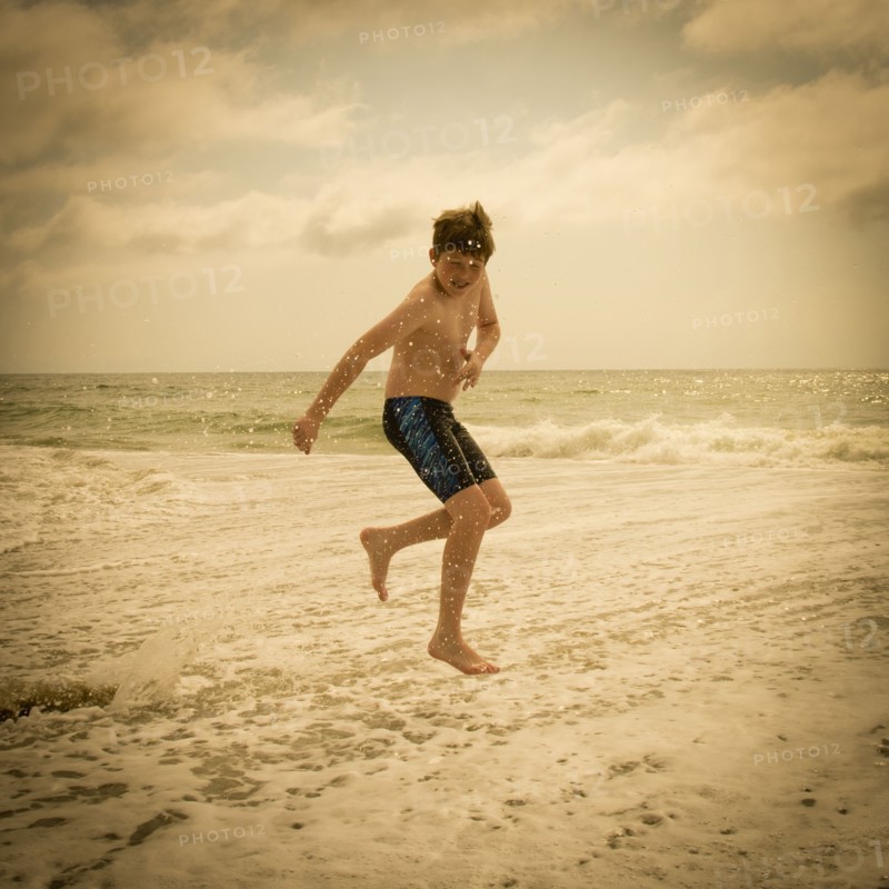 Caucasian boy jumping and splashing in ocean waves