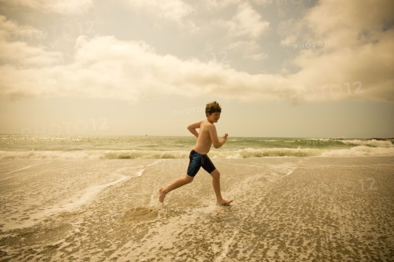 Caucasian boy running in ocean waves