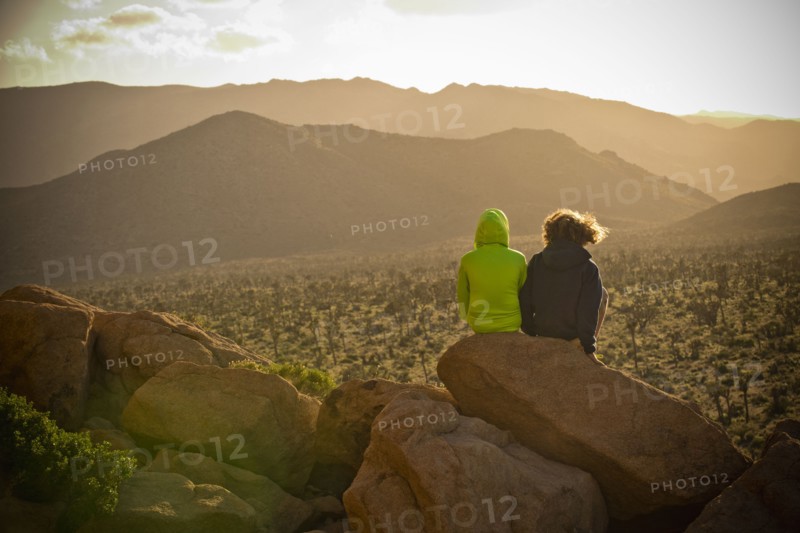 Boys sitting on rock admiring desert landscape