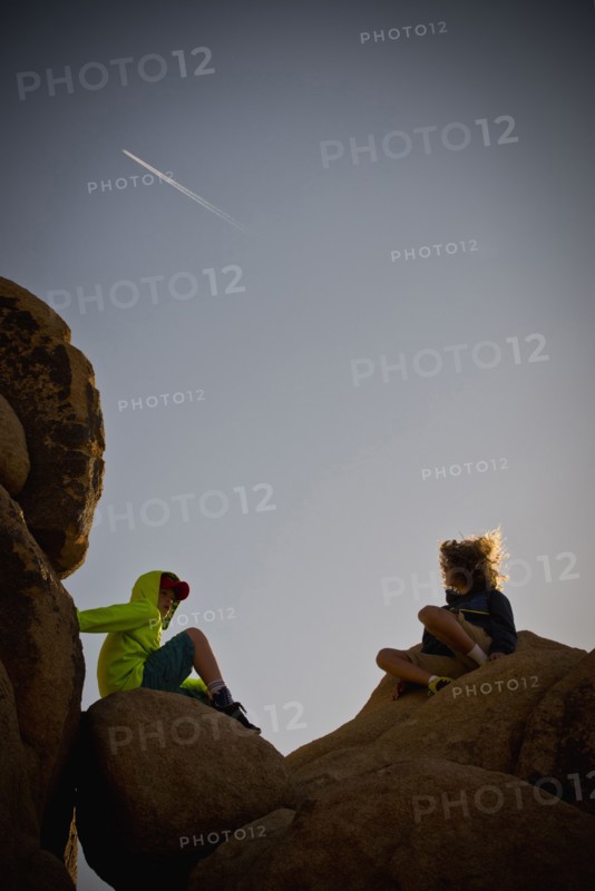 Boys sitting on rocks under blue sky