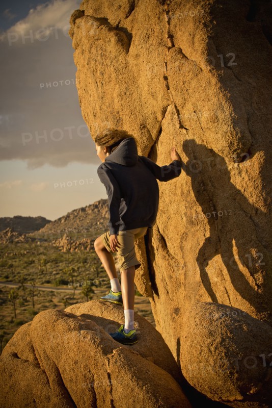 Mixed race boy standing on rock in desert