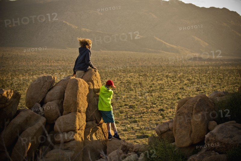 Boys standing on rocks admiring desert landscape