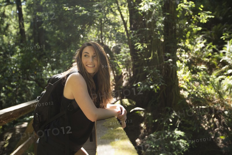Caucasian woman standing on wooden bridge in forest