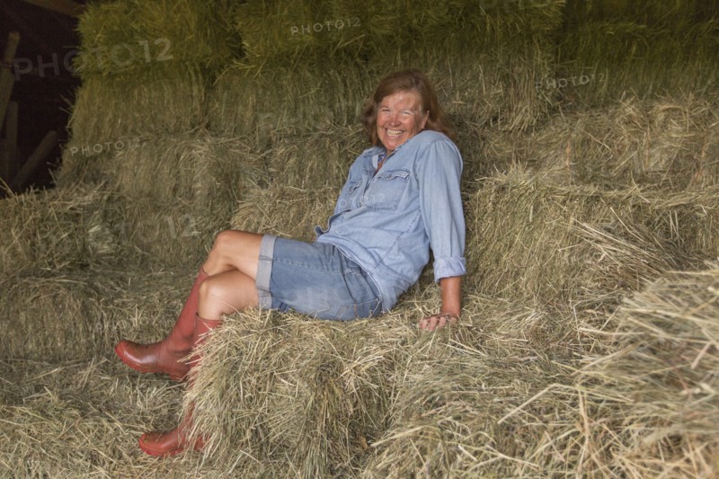 Older Caucasian woman sitting on hay bales