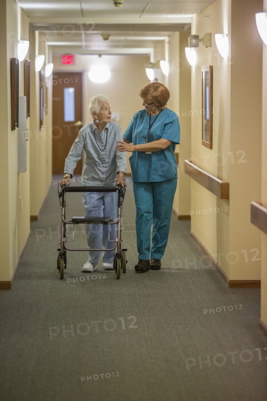 Older Caucasian woman walking with nurse in nursing home