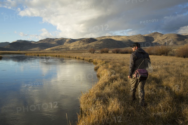 Man carrying fishing supplies near river