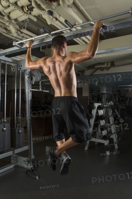 Caucasian athlete doing pull-ups in gymnasium