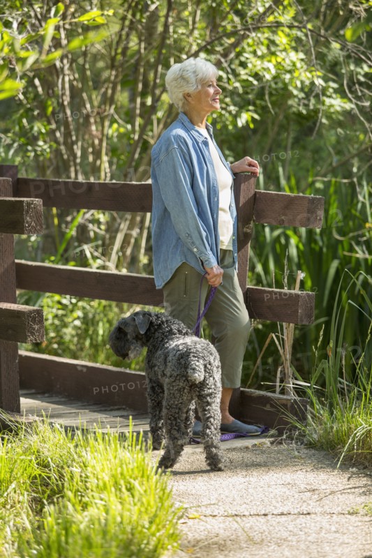 Older Caucasian woman walking dog in park