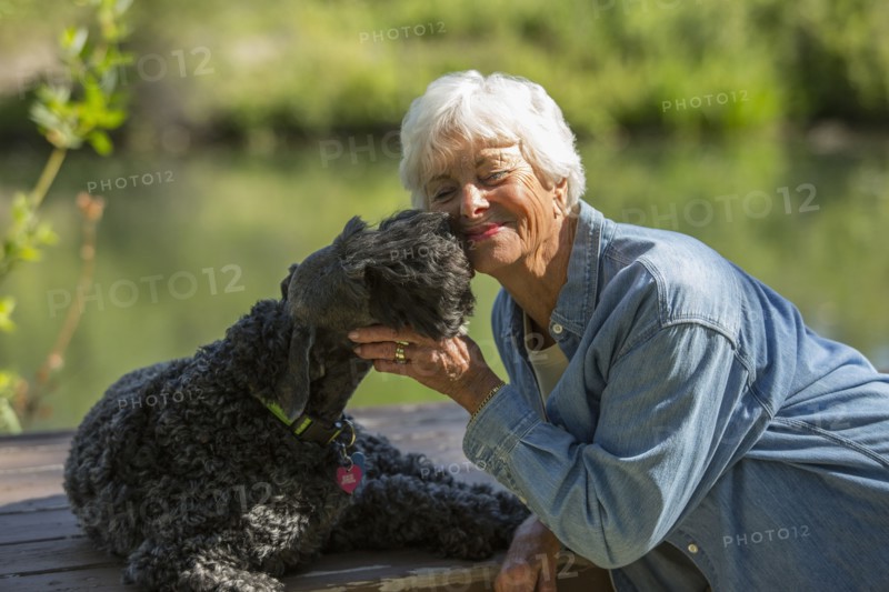 Older Caucasian woman hugging dog in park