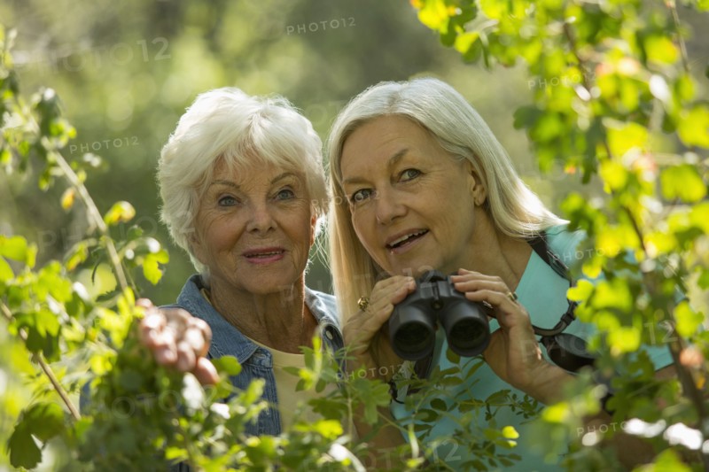 Older Caucasian women bird-watching outdoors