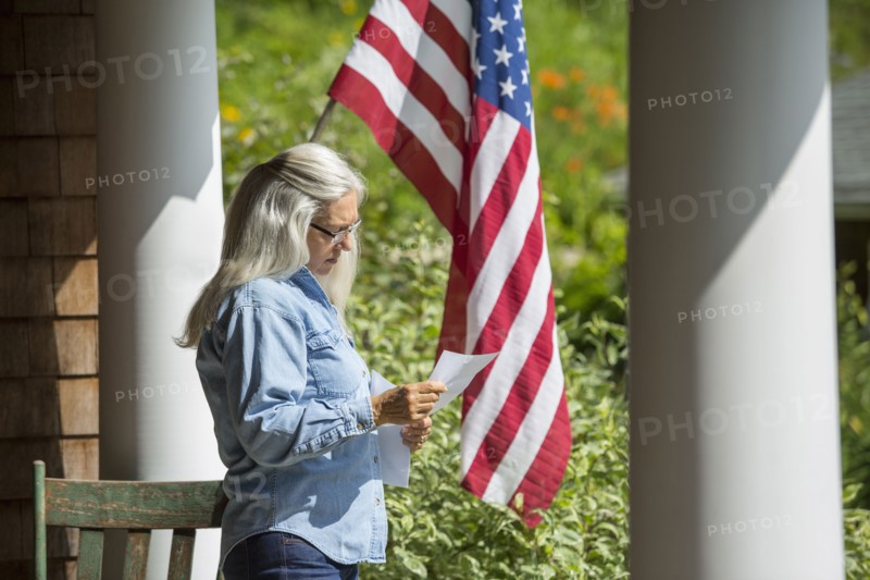Caucasian woman reading letter on porch