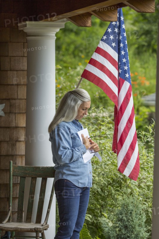 Caucasian woman reading letter on porch