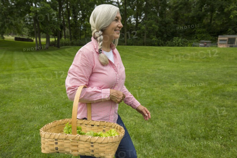 Caucasian woman carrying basket of vegetables in garden