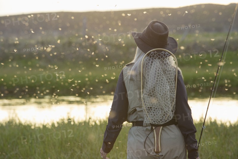 Caucasian woman wearing fishing gear in remote lake