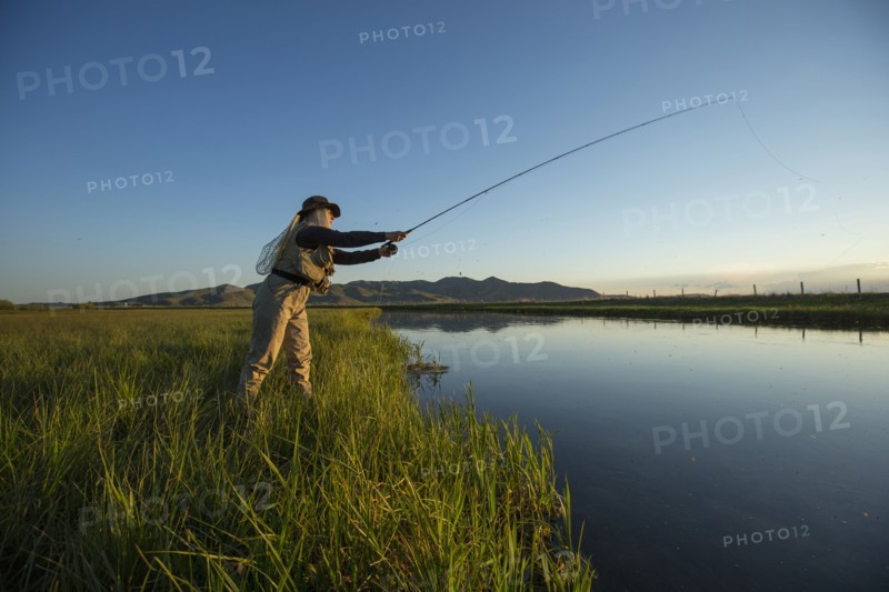 Caucasian woman casting fishing line in remote lake