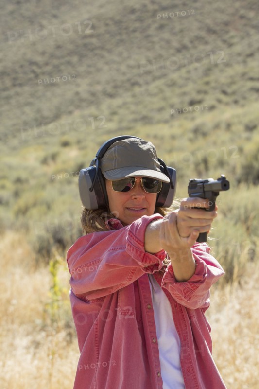 Caucasian woman aiming gun outdoors