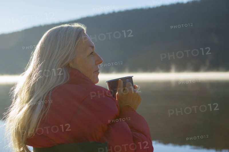 Caucasian woman drinking coffee at lake