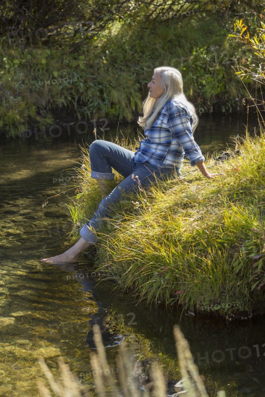 Caucasian woman dipping feet in river