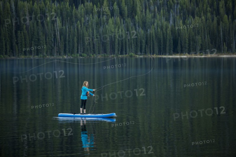 Caucasian woman fishing from paddle board in river