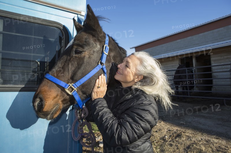 Caucasian woman petting horse on ranch