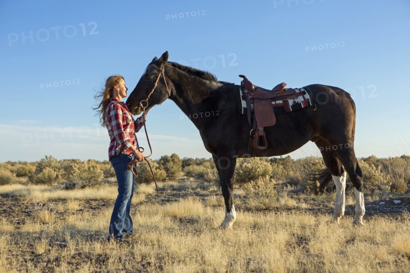 Caucasian woman standing with horse in field
