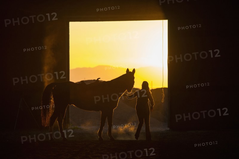 Caucasian woman riding horse in barn