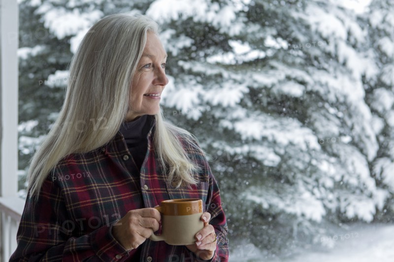 Older Caucasian woman drinking coffee on snowy patio