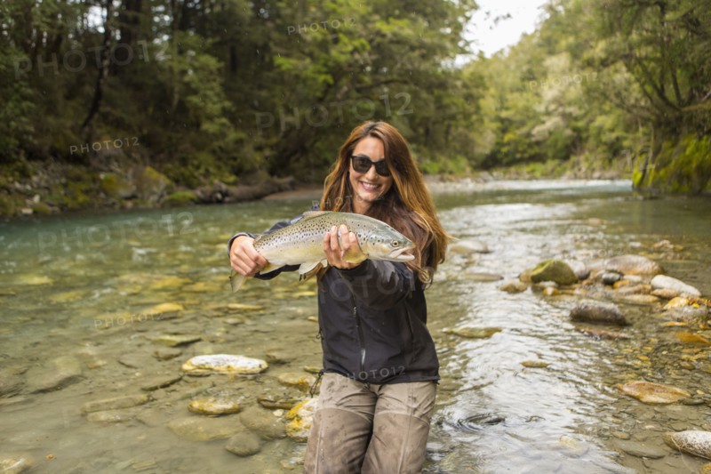 Caucasian woman catching fish in remote river