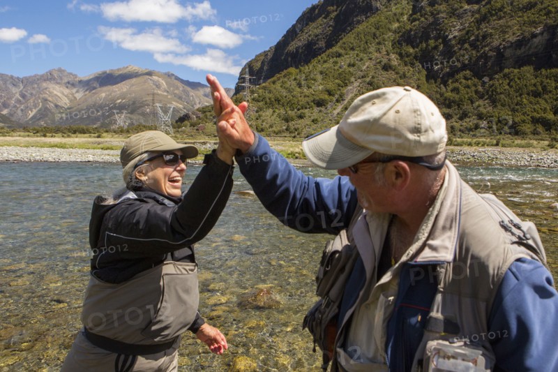 Caucasian couple high-fiving in remote river