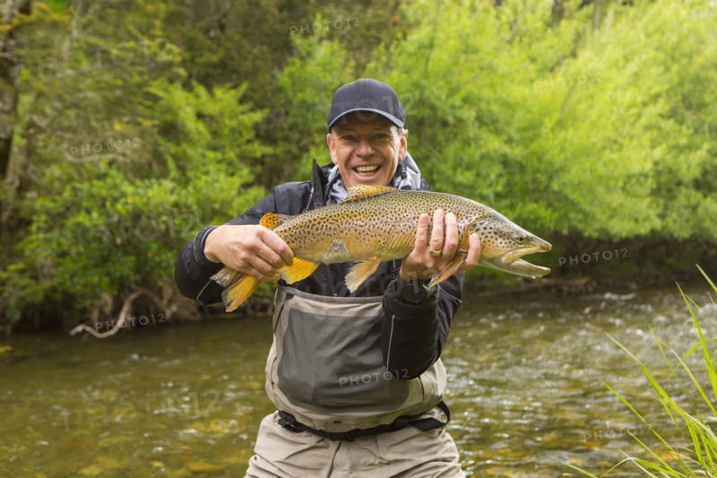 Caucasian man holding fish in remote river