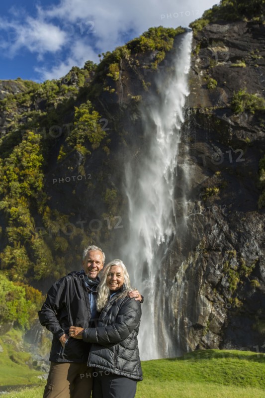 Caucasian couple hugging near remote waterfall