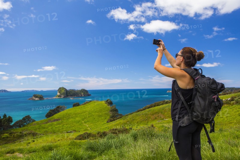 Caucasian hiker photographing cliff and seascape