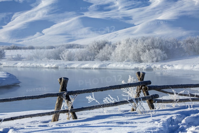 Fence and river in snowy rural landscape near river