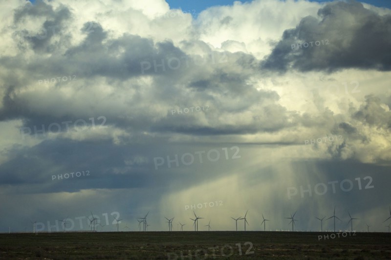 Storm clouds over wind turbines in rural landscape