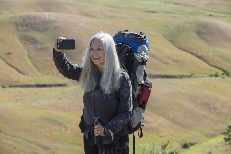 Older Caucasian woman hiking with backpack taking selfie