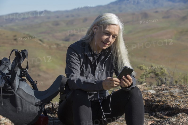 Older Caucasian woman listening to cell phone on mountain