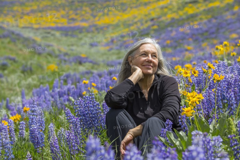 Caucasian woman smiling on hillside with wildflowers