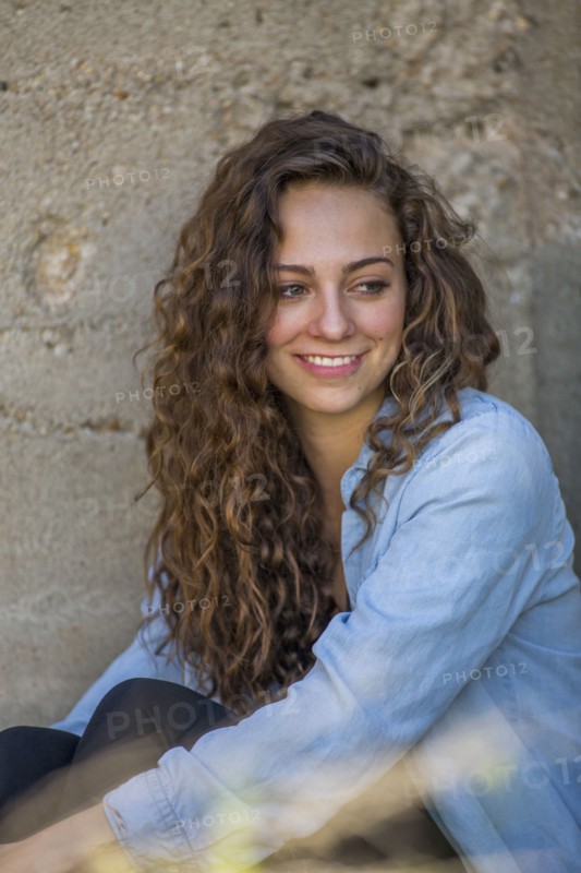 Caucasian woman sitting at concrete wall
