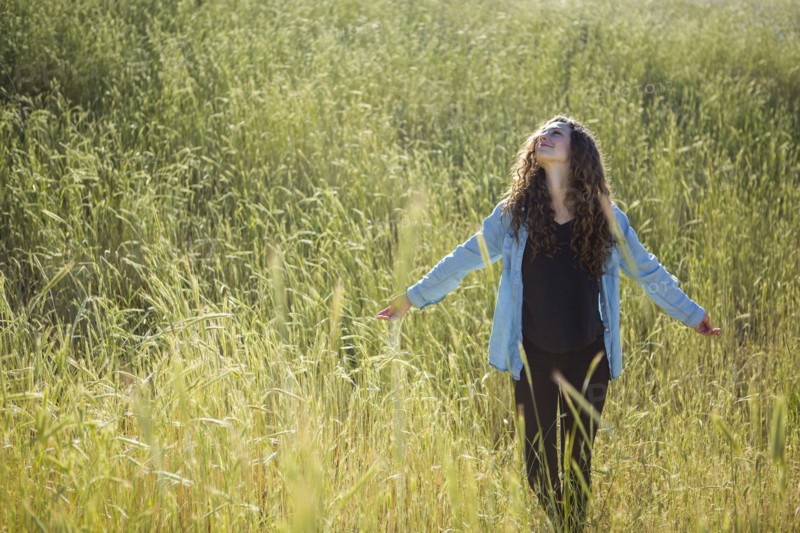 Carefree Caucasian woman walking in field of tall grass