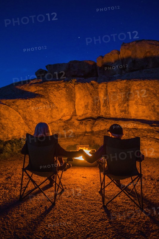 Caucasian couple holding hands near campfire at night