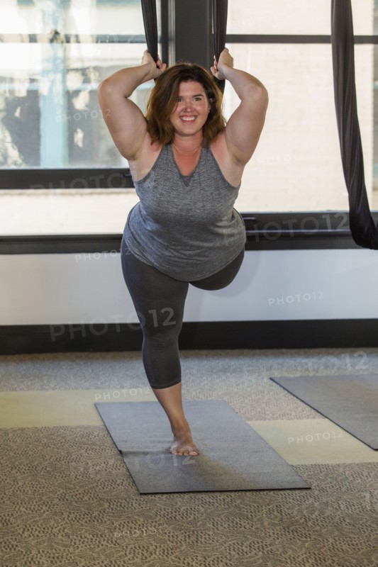 Woman performing yoga hanging from silks