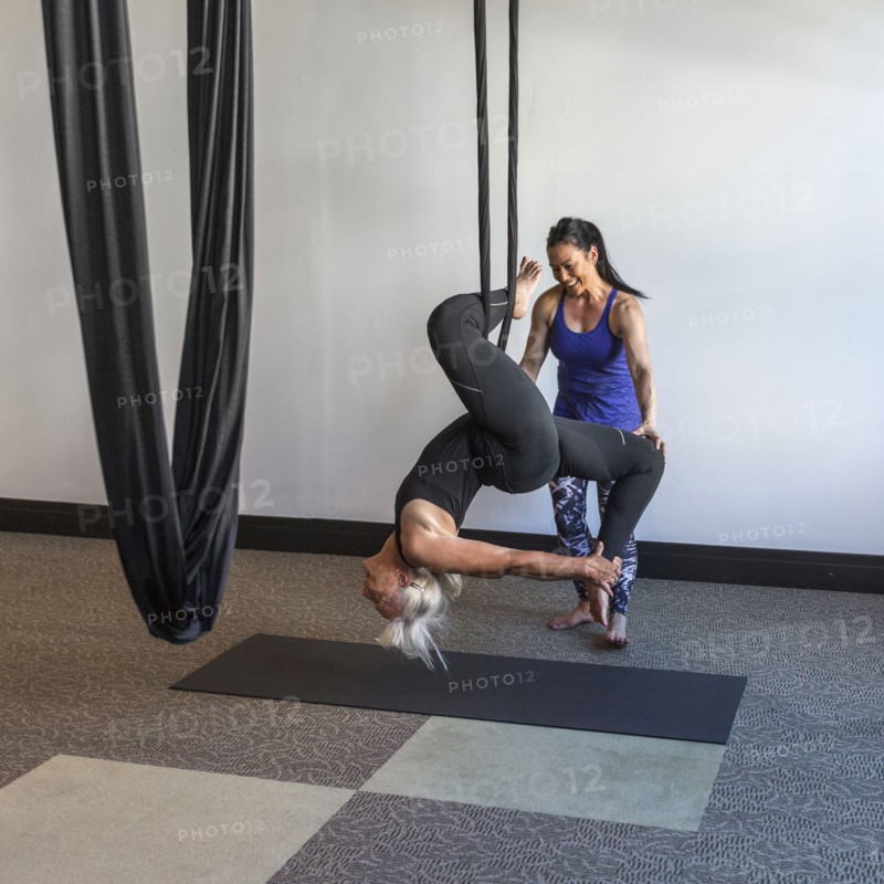 Instructor assisting student hanging from silks