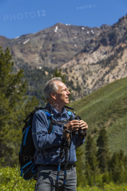 Caucasian man hiking in mountains with binoculars