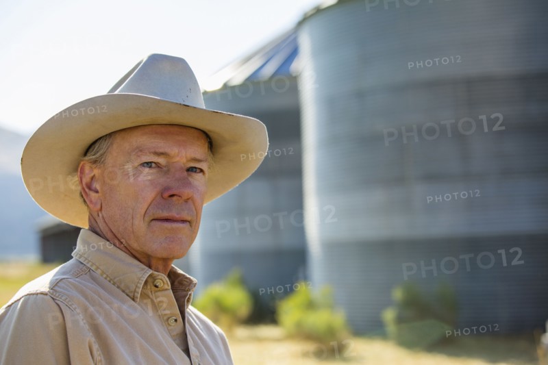 Serious Caucasian farmer near storage silos
