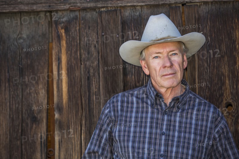 Serious Caucasian farmer near wooden fence
