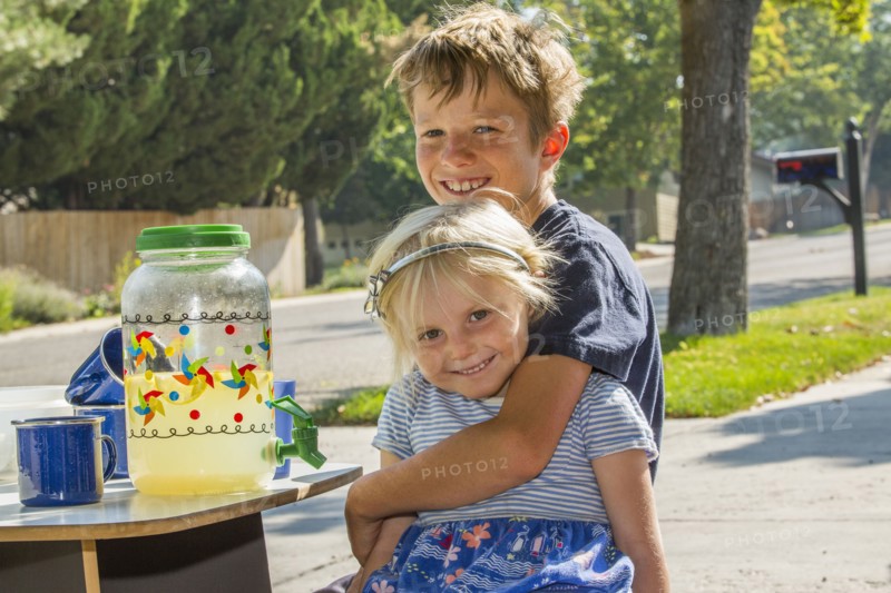 Smiling Caucasian boy hugging girl and selling lemonade