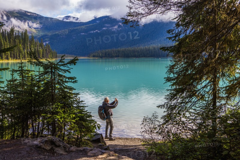 Caucasian man photographing mountain lake