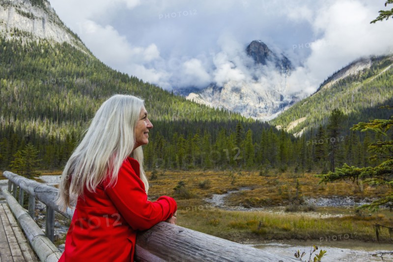 Caucasian woman leaning on wooden railing admiring mountain